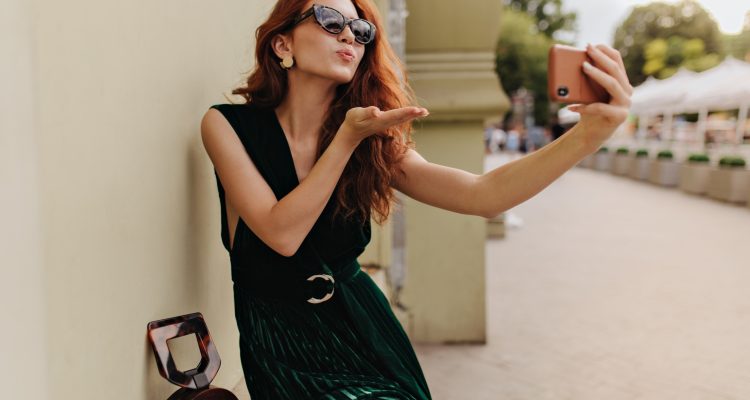 Sugar dating lifestyle – woman in sunglasses blowing a kiss on selfie